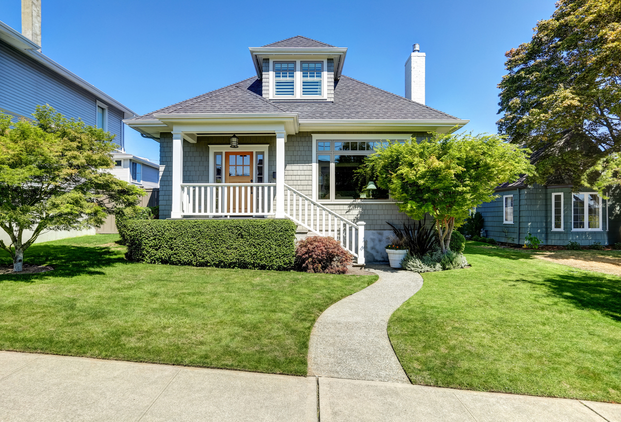 Single-family American craftsman house exterior. Blue sky background and nicely trimmed front yard. Northwest, USA